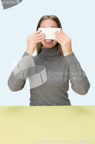 Image of The happy business woman sitting with mobile phone against pink background.