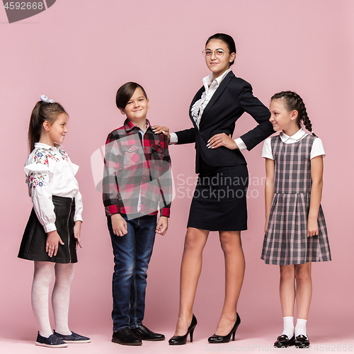 Image of Cute stylish children on pink studio background. The beautiful teen girls and boy standing together