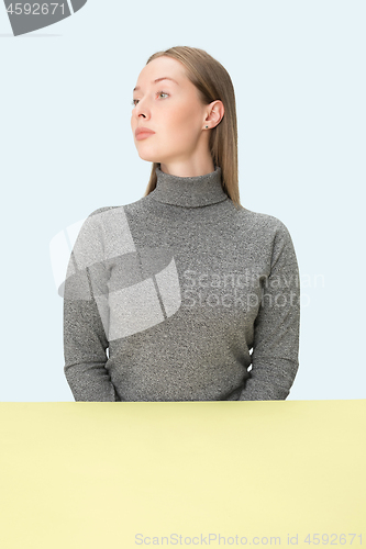 Image of Serious business woman sitting at a table on a pink background