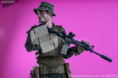 Image of soldier in action aiming laseer sight optics pink background