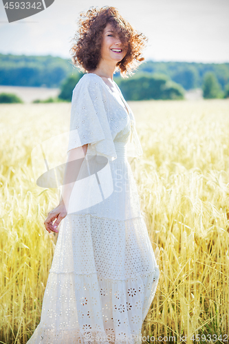 Image of happy smiling middle-aged woman in a white summer dress standing