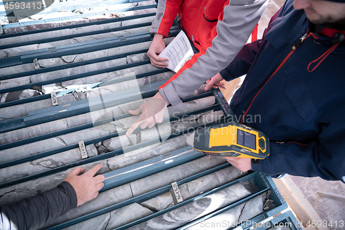 Image of team of mining  workers measuring drilled rock core