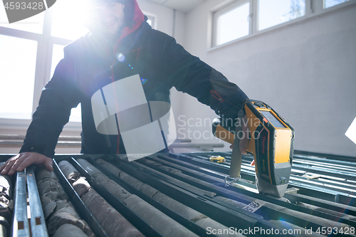 Image of team of mining  workers measuring drilled rock core