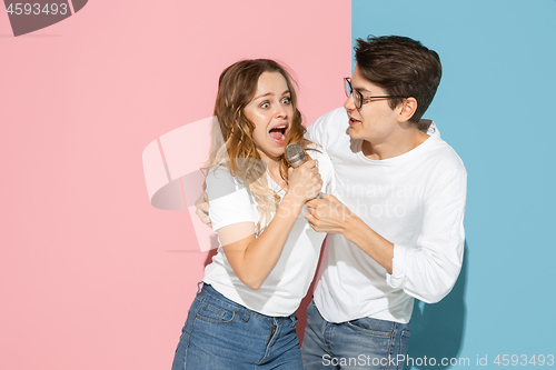 Image of Young emotional man and woman on pink and blue background