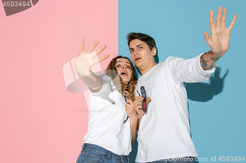 Image of Young emotional man and woman on pink and blue background
