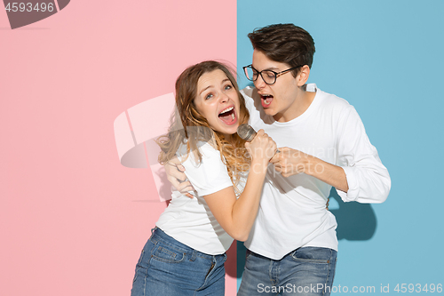 Image of Young emotional man and woman on pink and blue background