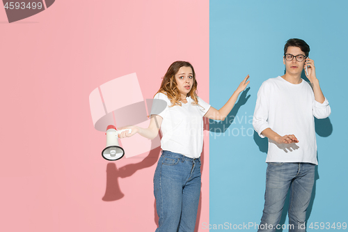 Image of Young emotional man and woman on pink and blue background