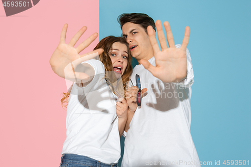 Image of Young emotional man and woman on pink and blue background