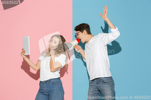 Image of Young emotional man and woman on pink and blue background