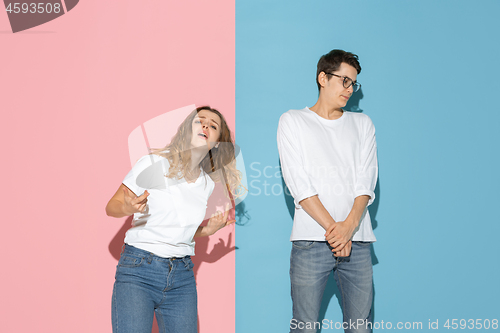 Image of Young emotional man and woman on pink and blue background