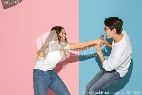 Image of Young emotional man and woman on pink and blue background