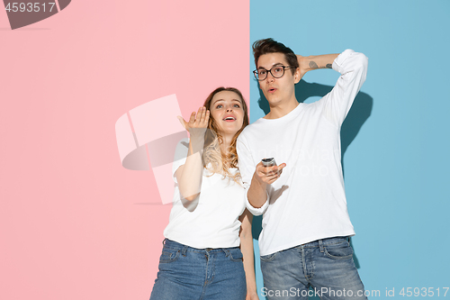 Image of Young emotional man and woman on pink and blue background