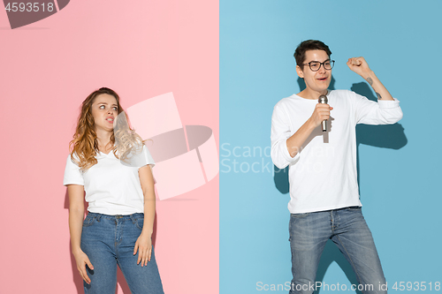 Image of Young emotional man and woman on pink and blue background