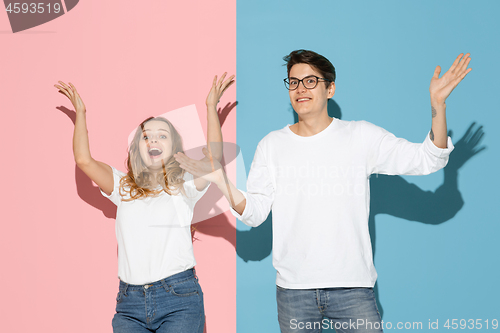 Image of Young emotional man and woman on pink and blue background