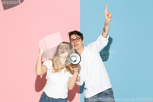 Image of Young emotional man and woman on pink and blue background