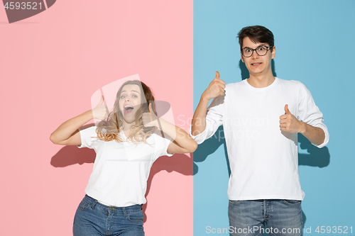 Image of Young emotional man and woman on pink and blue background