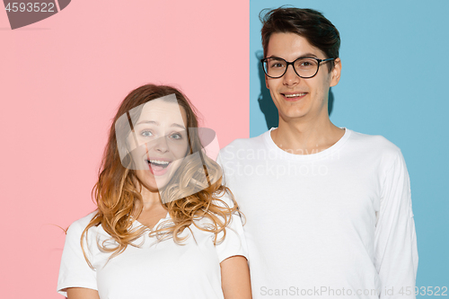 Image of Young emotional man and woman on pink and blue background