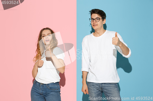 Image of Young emotional man and woman on pink and blue background