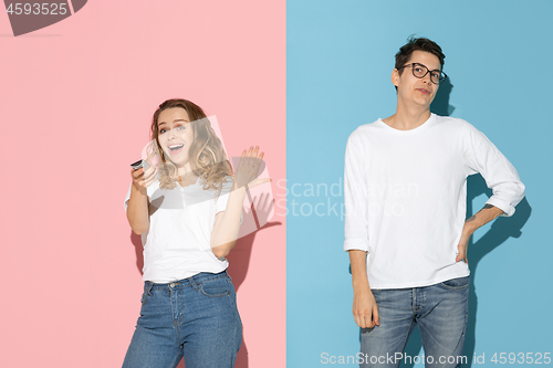 Image of Young emotional man and woman on pink and blue background