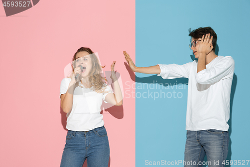 Image of Young emotional man and woman on pink and blue background