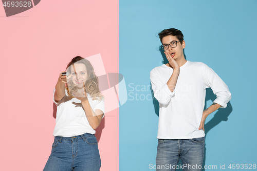 Image of Young emotional man and woman on pink and blue background