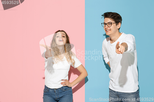 Image of Young emotional man and woman on pink and blue background