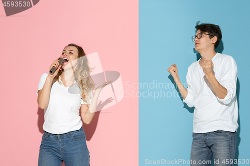 Image of Young emotional man and woman on pink and blue background