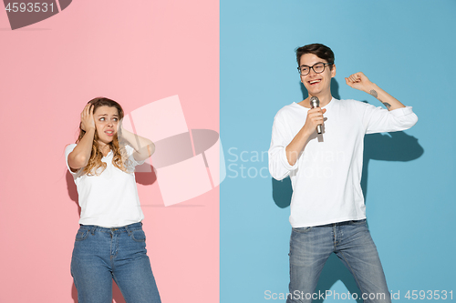 Image of Young emotional man and woman on pink and blue background