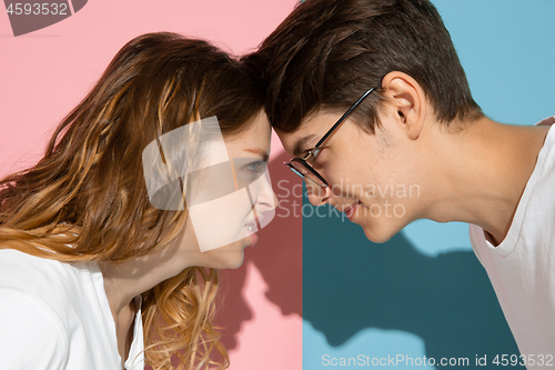 Image of Young emotional man and woman on pink and blue background