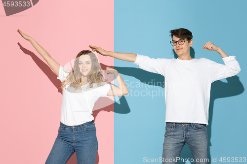 Image of Young emotional man and woman on pink and blue background