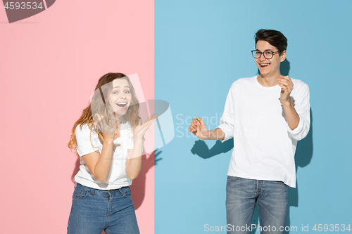 Image of Young emotional man and woman on pink and blue background