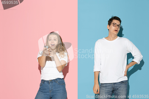Image of Young emotional man and woman on pink and blue background