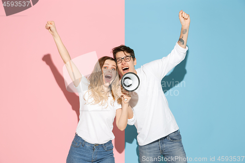 Image of Young emotional man and woman on pink and blue background