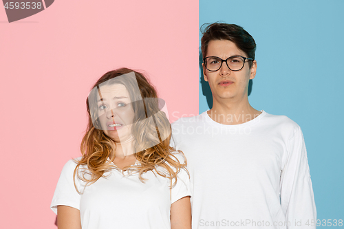 Image of Young emotional man and woman on pink and blue background