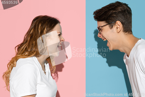 Image of Young emotional man and woman on pink and blue background