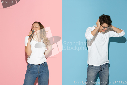 Image of Young emotional man and woman on pink and blue background