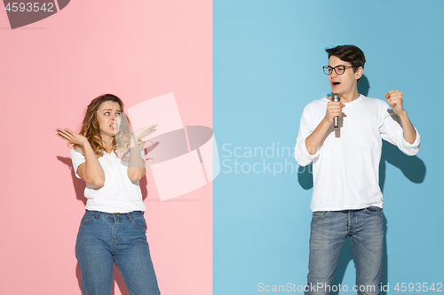 Image of Young emotional man and woman on pink and blue background