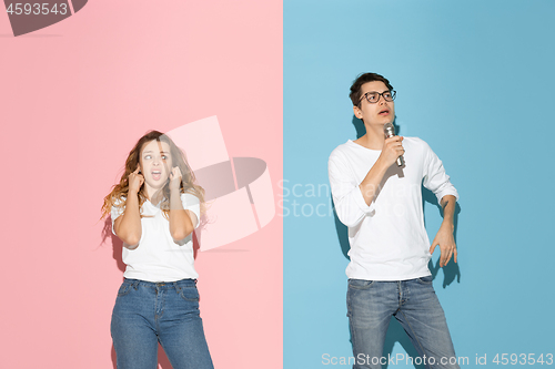 Image of Young emotional man and woman on pink and blue background