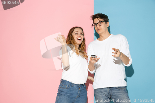 Image of Young emotional man and woman on pink and blue background