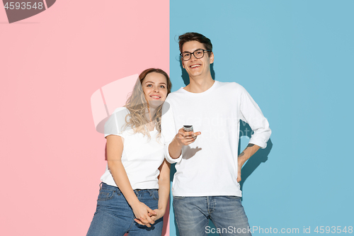 Image of Young emotional man and woman on pink and blue background