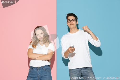 Image of Young emotional man and woman on pink and blue background