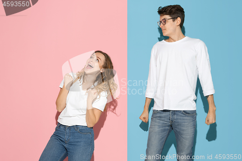 Image of Young emotional man and woman on pink and blue background