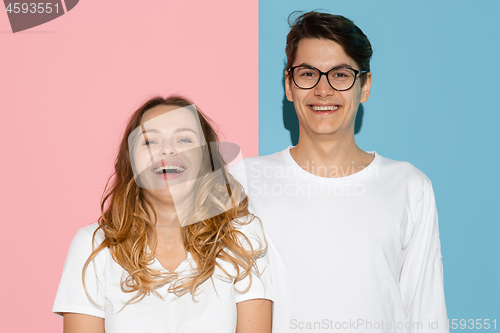 Image of Young emotional man and woman on pink and blue background