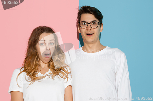 Image of Young emotional man and woman on pink and blue background