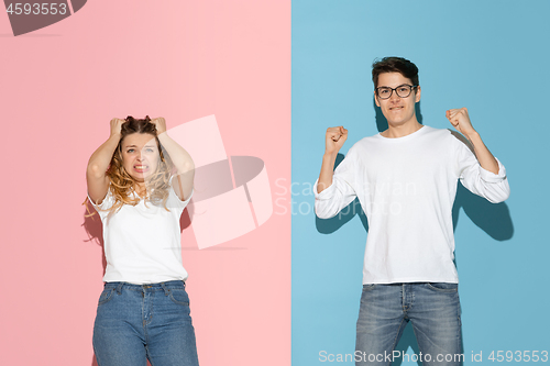 Image of Young emotional man and woman on pink and blue background