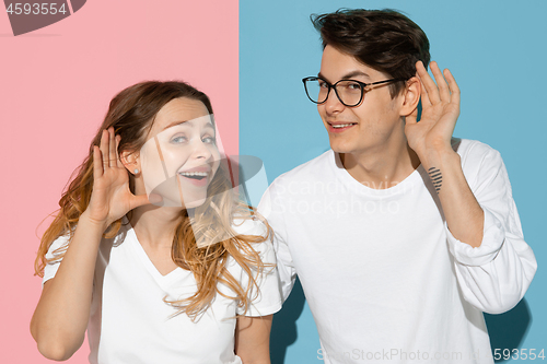 Image of Young emotional man and woman on pink and blue background
