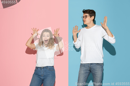 Image of Young emotional man and woman on pink and blue background