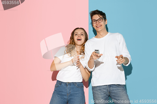 Image of Young emotional man and woman on pink and blue background