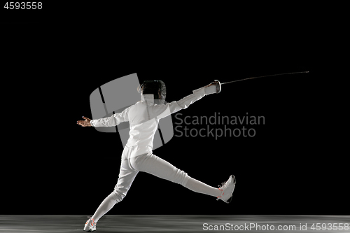 Image of Teen girl in fencing costume with sword in hand isolated on black background