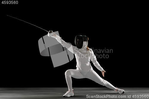 Image of Teen girl in fencing costume with sword in hand isolated on black background